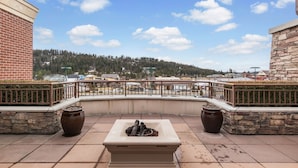 A rooftop patio with a stone planter, a seating area, and a view of a forested hillside. - Fabulous Riverstone Retreat (Coeur d'Alene)