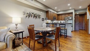 A modern kitchen with wooden cabinets, a central island, and a dining area with a round table and chairs. - Fabulous Riverstone Retreat (Coeur d'Alene)