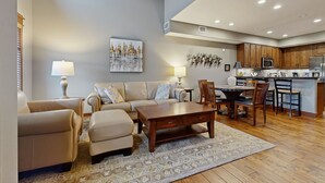 A living room with a sofa, coffee table, and a dining area with chairs and a table. - Fabulous Riverstone Retreat (Coeur d'Alene)