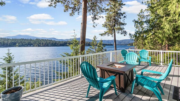A deck with a table and chairs, overlooking a lake with mountains in the background. - Lakeside Cabin in Hayden (Hayden)