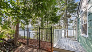 A wooden deck with a railing, a fenced area, and a view of a body of water. - Lakeside Cabin in Hayden (Hayden)