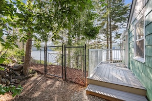 A wooden deck with a railing, a fenced area, and a view of a body of water. - Lakeside Cabin in Hayden (Hayden)