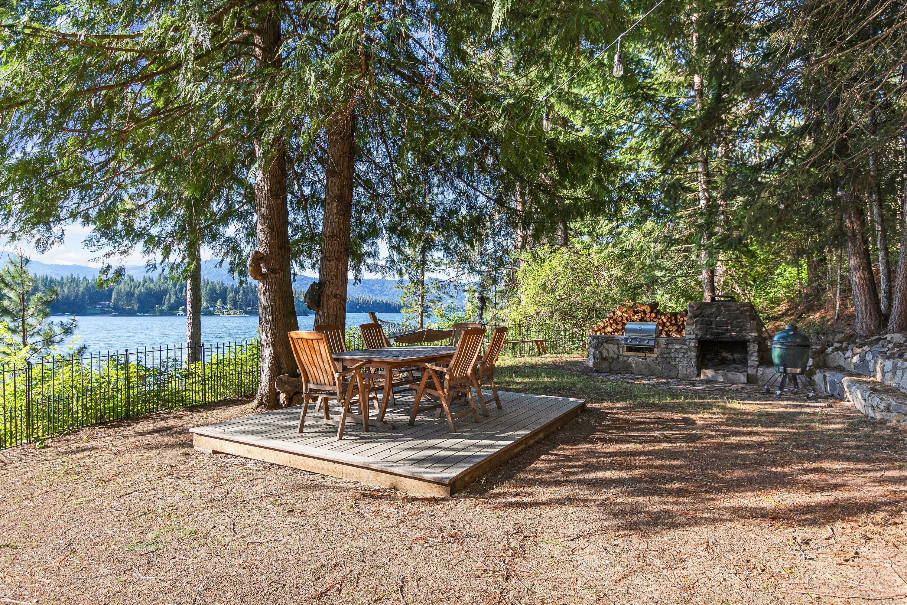 Une terrasse avec une table et des chaises, une cheminée en pierre et un espace barbecue.