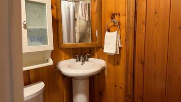 A bathroom with wooden walls, a white sink, a mirror, and a towel rack.