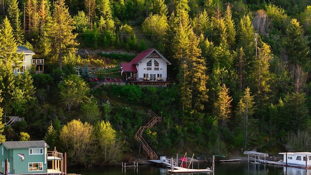 En hytte ved søen med en ankomstbro, omgivet af tæt skov.