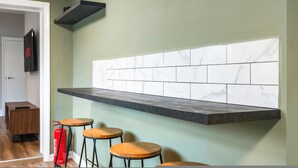 A kitchen with a marble backsplash, a dark countertop, and wooden stools. - Spacious 5BR Home With Parking in Central Horsham (Horsham)