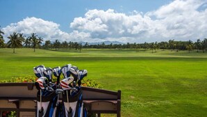 Ein Golfplatz mit einer Bank und Golfbags im Vordergrund.