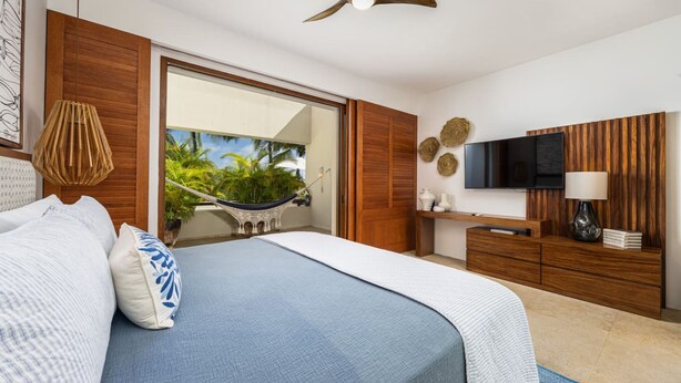 Ein Schlafzimmer mit Bett, Fernseher, Deckenventilator, Holzschrank und einem großen Spiegel.