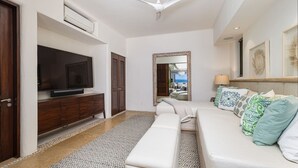 A modern living room with a flat-screen TV, a ceiling fan, a sofa with patterned cushions, a patterned rug, and a large mirror. - Casa Sole in Punta Mita (Punta de Mita)