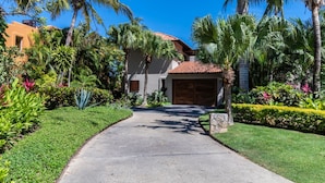 A house with a paved driveway, palm trees, and a garage. - Casa Sole in Punta Mita (Punta de Mita)