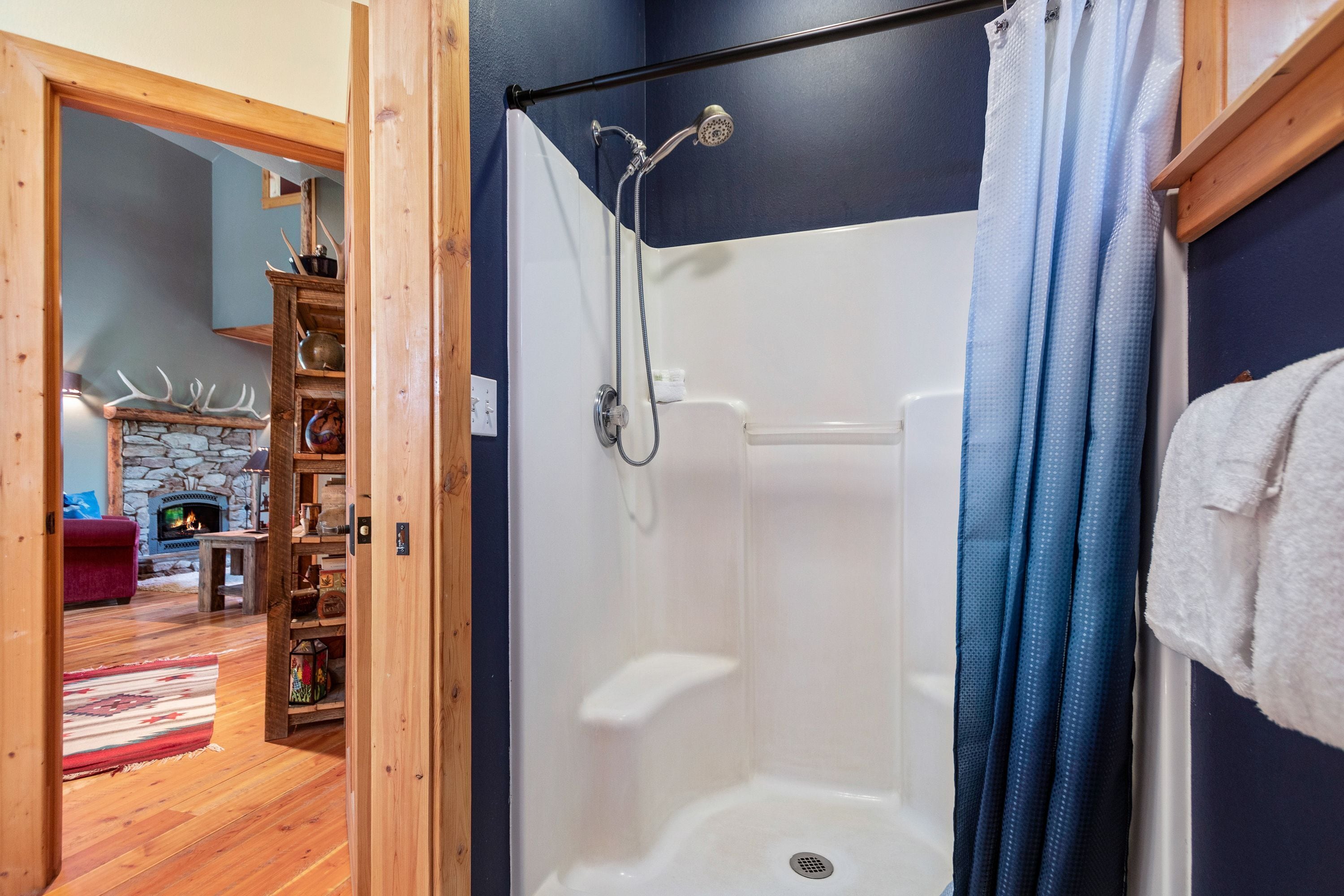 A room with a shower, a stone fireplace, and a wooden floor.