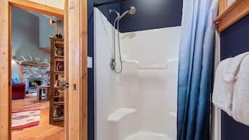 A room with a shower, a stone fireplace, and a wooden floor.