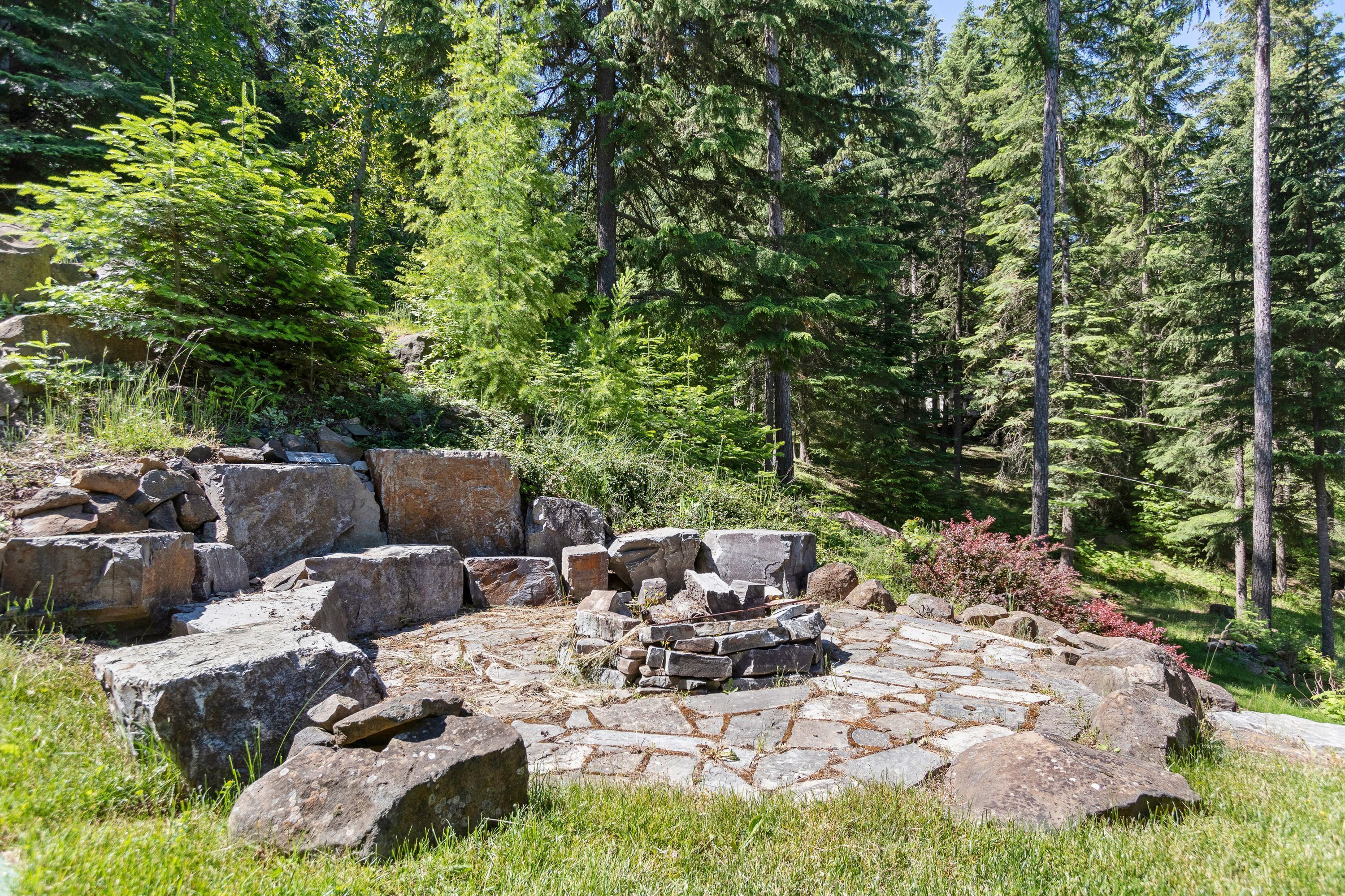 A stone-paved area with scattered rocks and trees in the background.