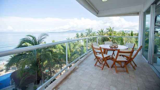 A balcony with a table and chairs overlooking a beach and ocean. - Beautiful Beachfront 3 bd Condo in Nuevo Vallarta (Nuevo Nayarit)