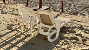A beach scene with a thatched umbrella, white lounge chairs, and a view of the ocean. - Beautiful Beachfront 3 bd Condo in Nuevo Vallarta (Nuevo Nayarit)