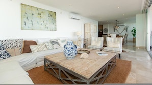 A living room with a sofa, a coffee table, and a painting on the wall. - Beautiful Beachfront 3 bd Condo in Nuevo Vallarta (Nuevo Nayarit)