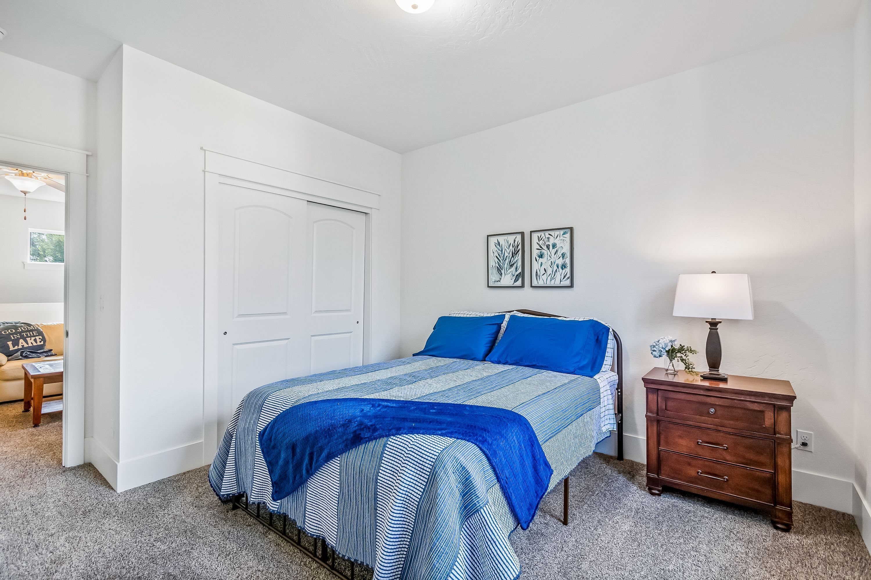 Une chambre à coucher avec un lit, une table de chevet, une commode et une porte.