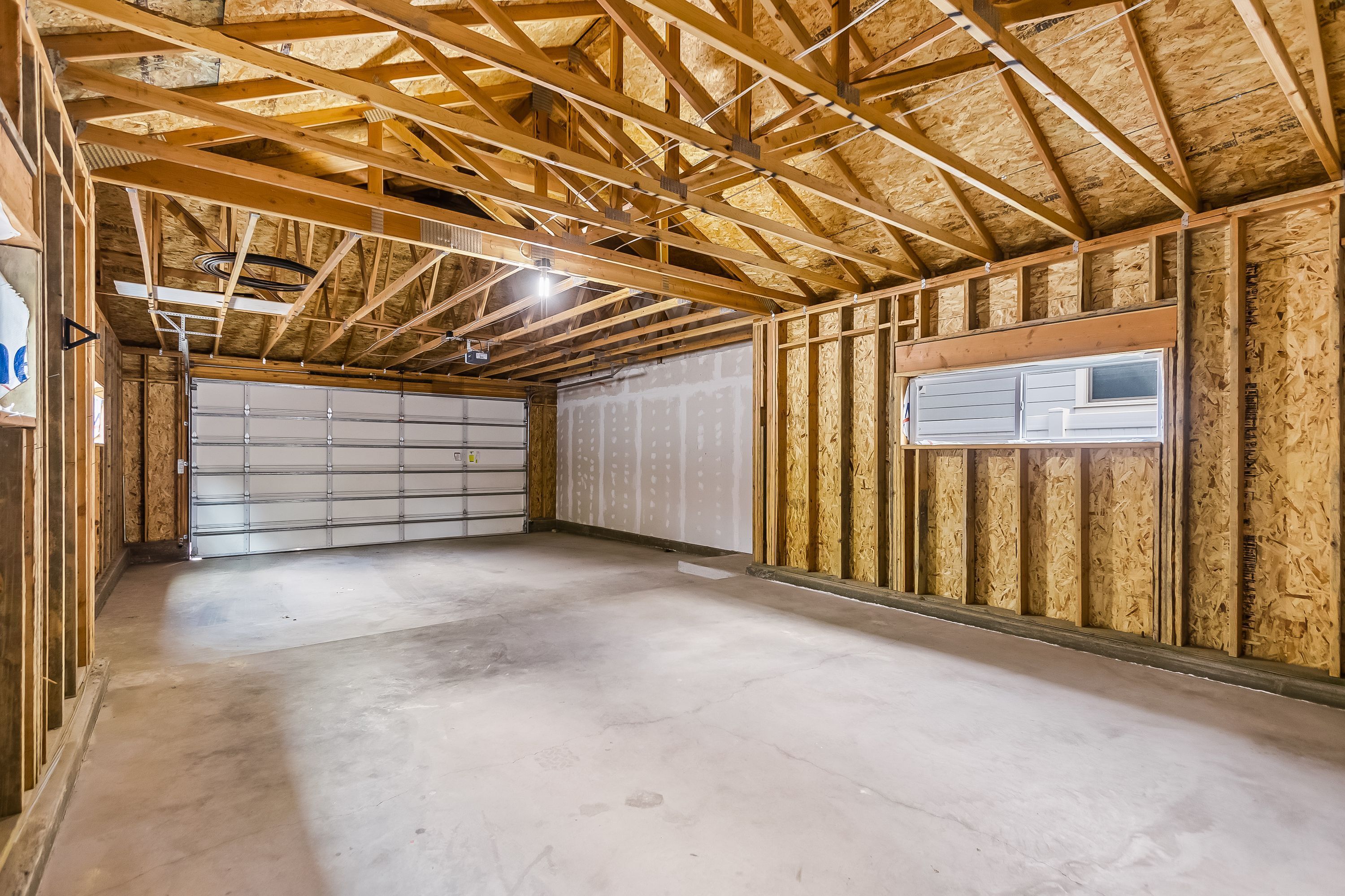 A garage with wooden framing, a concrete floor, and a garage door.