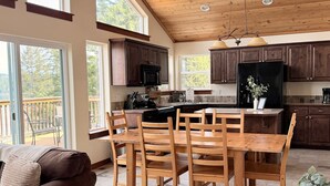 A spacious kitchen with wooden cabinets, a dining table with chairs, and a view of the outdoors.