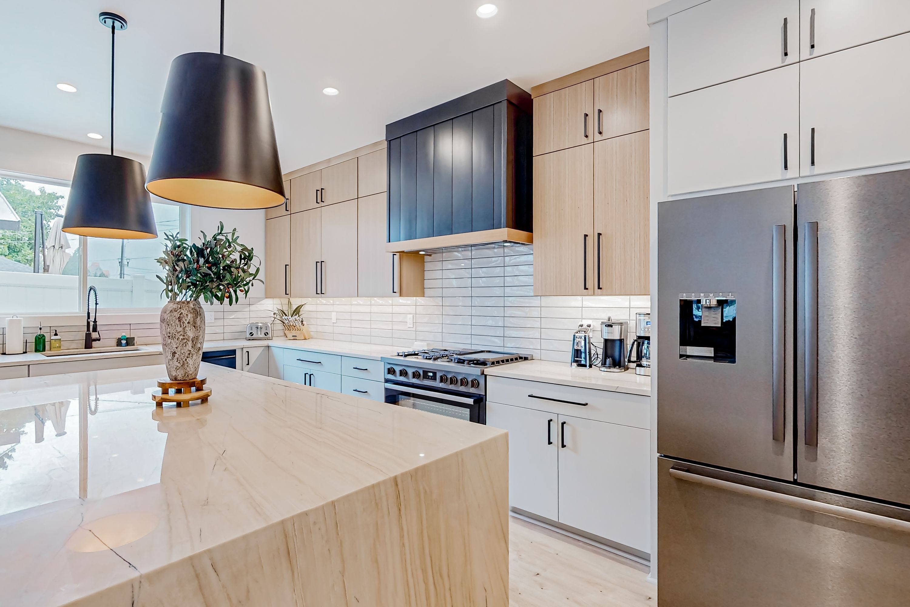 Cozinha moderna com ilha central, eletrodomésticos de aço inoxidável e iluminação pendente.
