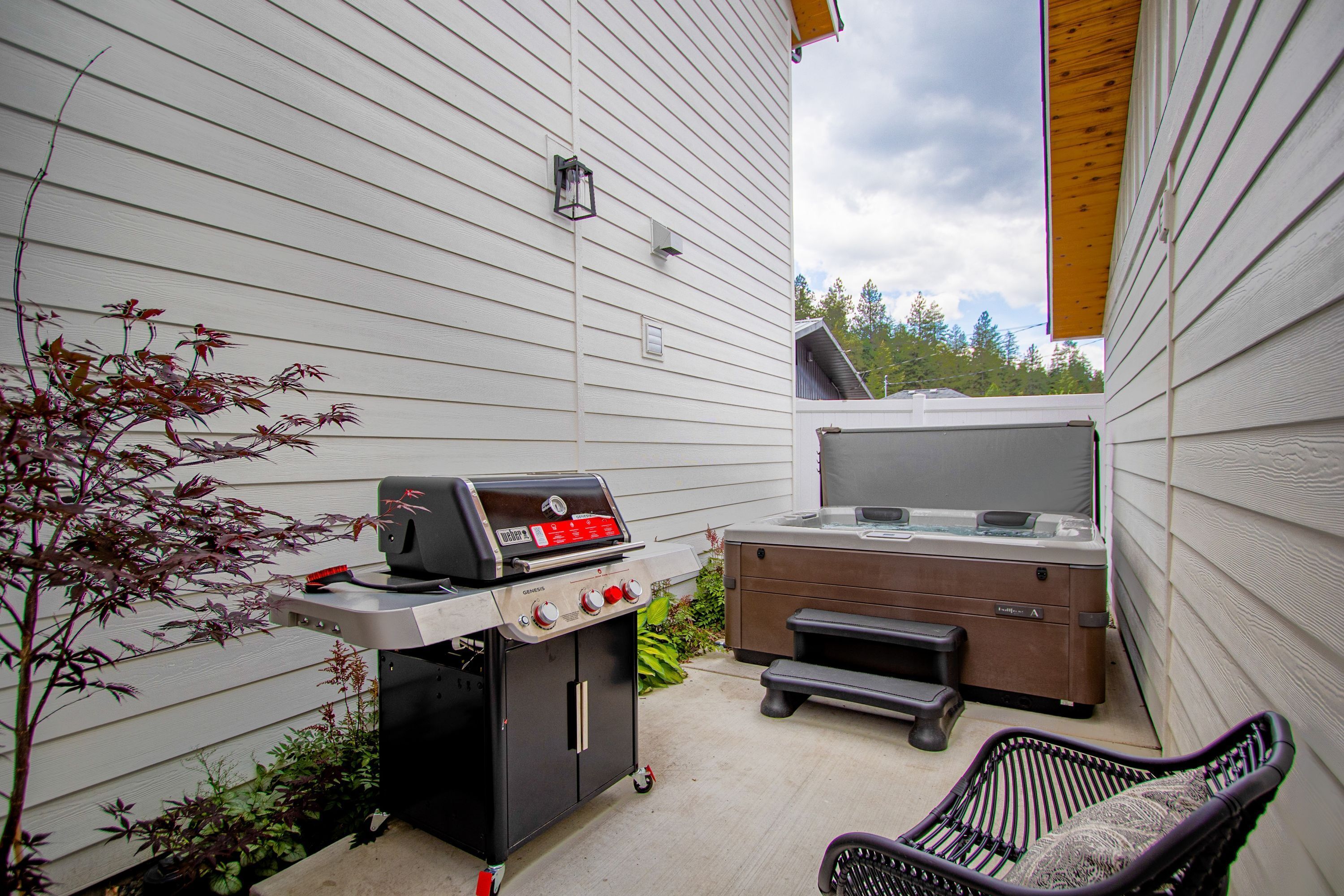 A patio with a grill, a hot tub, and a chair.