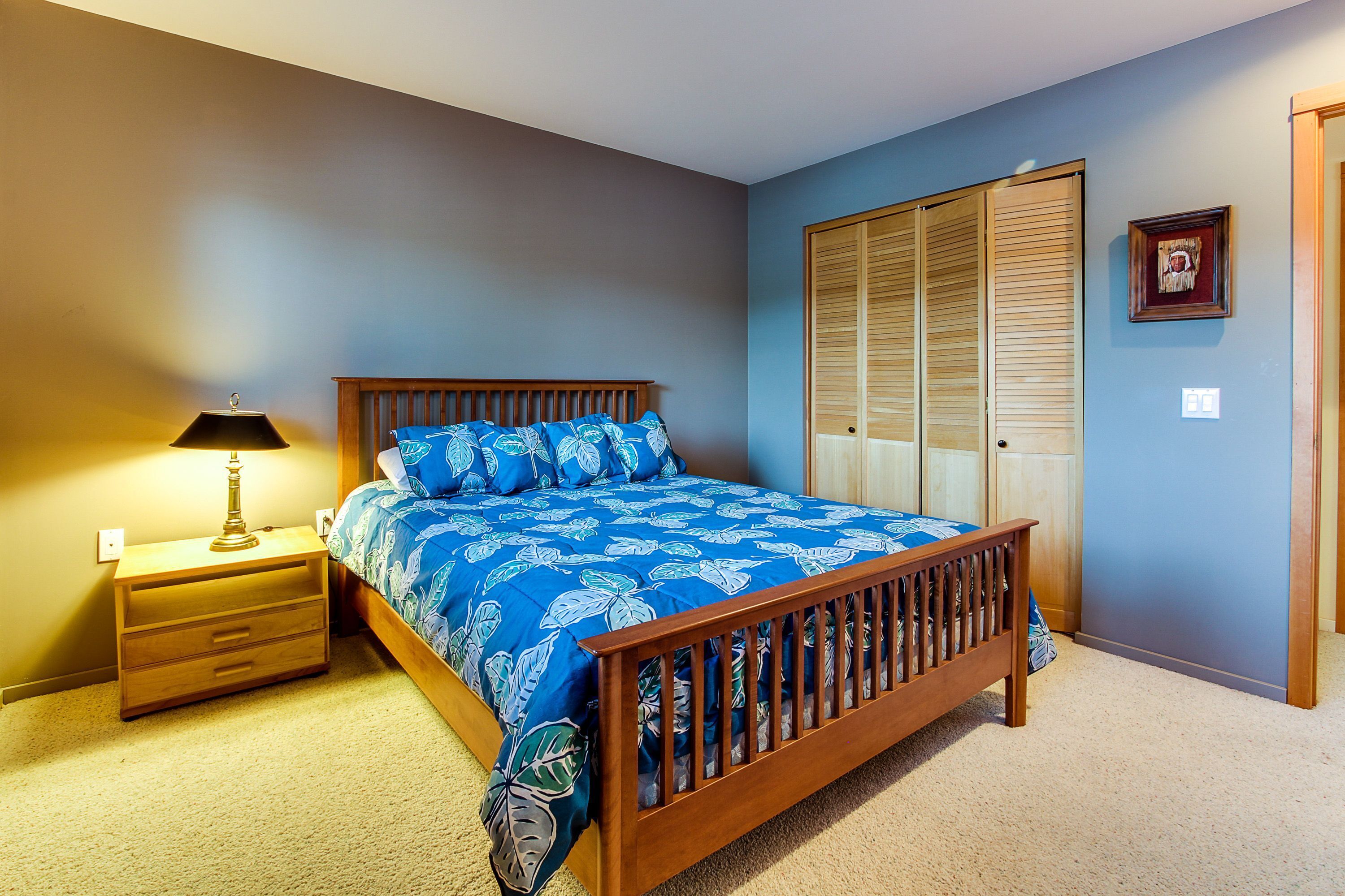 A bedroom with a wooden bed, a nightstand, a lamp, and a wardrobe.