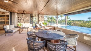 Un espacio al aire libre cubierto con mobiliario de mimbre, una piscina y vistas a palmeras.