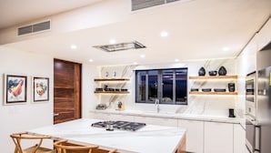 Una cocina moderna con una isla central, armarios blancos y una ventana con vistas a la ciudad.