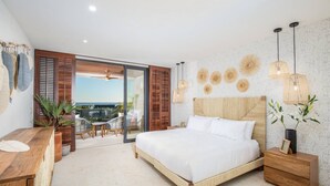 Un dormitorio con una cama grande, una mesita de noche de madera, un escritorio y vistas al exterior a través de una puerta corredera.