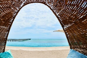 A beach view through a woven structure with a pier in the distance. - Condo Los Arboles -hsk 6 Seater Golf Cart Included (Punta de Mita)