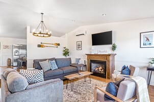 Un salón con chimenea, sofá, mesa de centro y televisor.