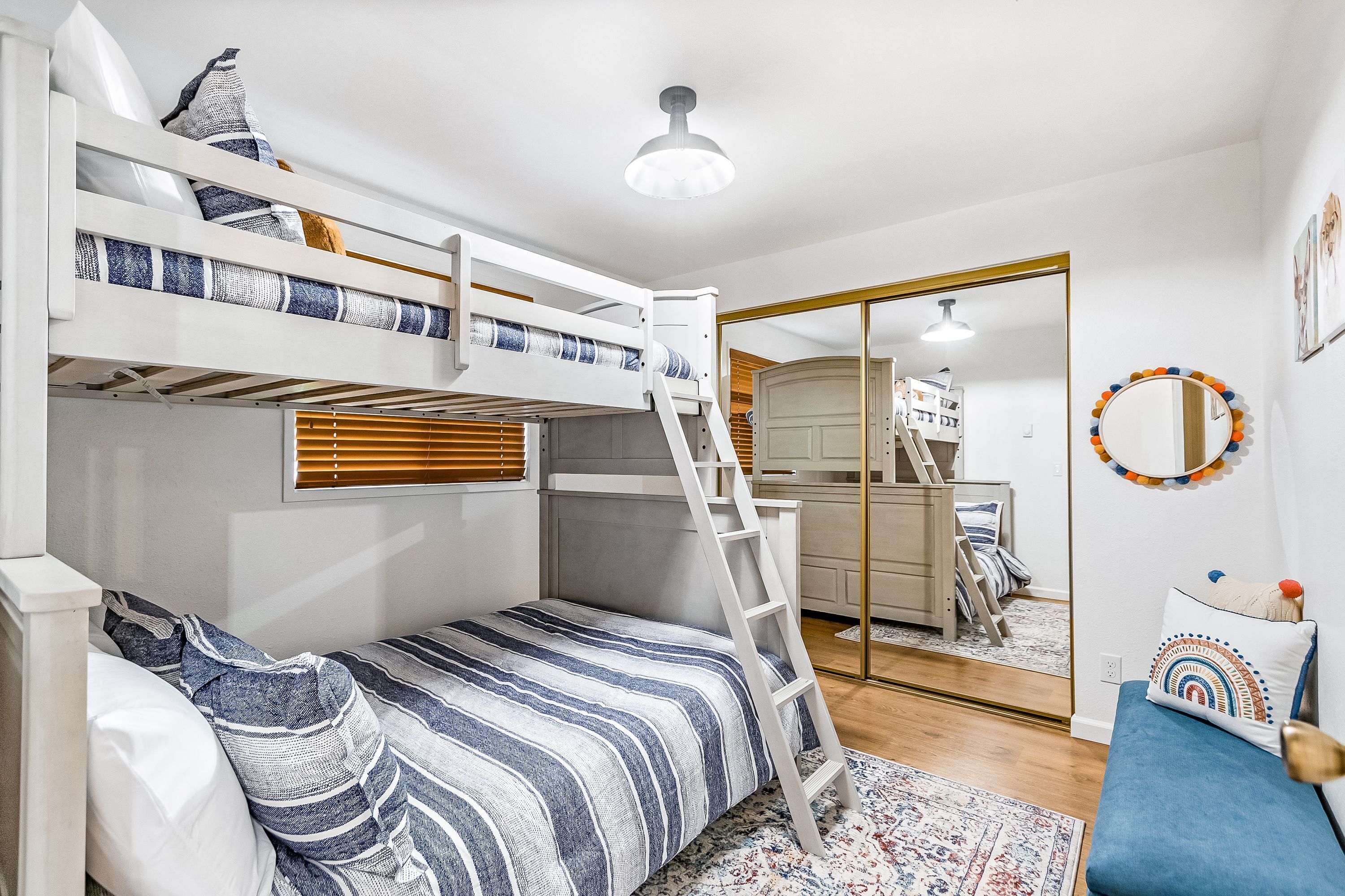 A bunk bed room with a ladder, a small desk, and a mirror.