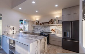 A modern kitchen with a marble island, built-in oven, and a large refrigerator. - Very Private 4bed 4 5bath Villa Casa Libre Las Palmas 22 (Punta de Mita)