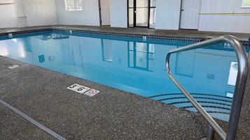 An indoor swimming pool with a clear water surface, marked depth lines, and a metal pool ladder.
