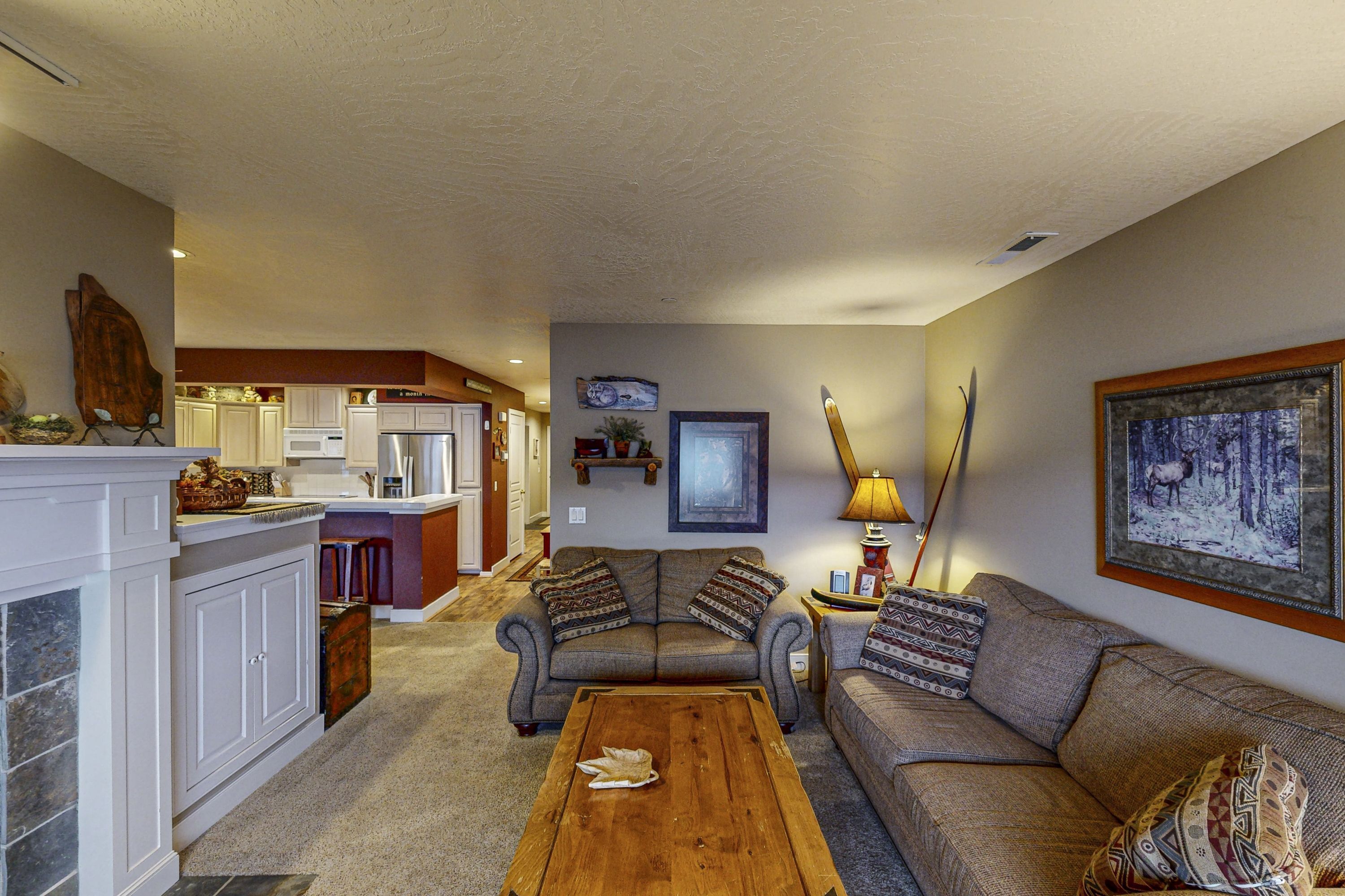 A living room with a sofa, coffee table, and a kitchen in the background.