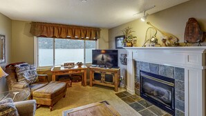Un salón con chimenea, televisor y vistas al exterior.