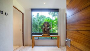 Una estatua en un banco en un pasillo con vistas a la vegetación a través de una ventana.