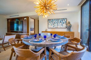 A dining area with a round table, wooden chairs, and blue glassware. - 3 bd Condo With Ocean Views HK (San Marcos)