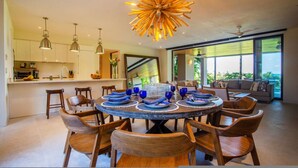 Un comedor moderno con una mesa redonda, sillas de madera y cristalería azul.