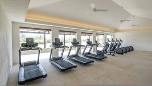 A gym with treadmills and stationary bikes arranged in rows, large windows, and ceiling fans. - 3bd Condo Ocean Views Pool HK - Tower 5 (Punta de Mita)