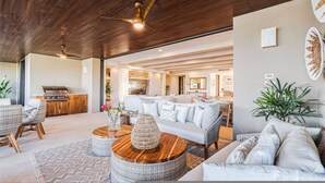 A spacious living area with a ceiling fan, wicker furniture, a white sofa, and a kitchen visible through an open doorway. - 3bd Condo Ocean Views Pool HK - Tower 5 (Punta de Mita)
