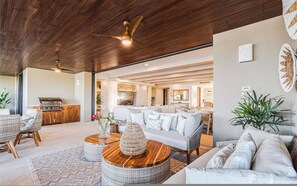 A spacious living area with a ceiling fan, wicker furniture, a white sofa, and a kitchen visible through an open doorway. - 3bd Condo Ocean Views Pool HK - Tower 5 (Punta de Mita)