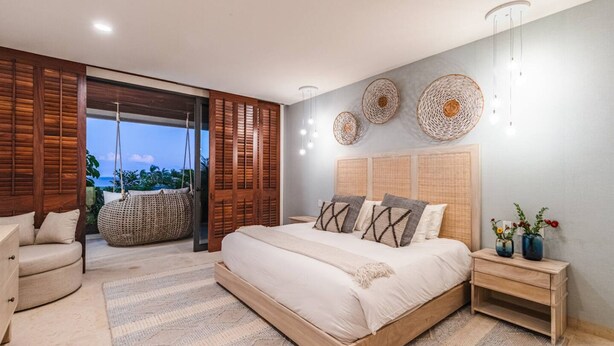 A bedroom with a large bed, wooden headboard, bedside tables, a hanging chair, and a view of the outdoors. - 3bd Condo Ocean Views Pool HK - Tower 5 (Punta de Mita)