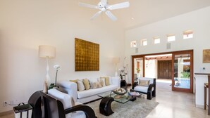 A spacious living room with a white sofa, black armchairs, a glass coffee table, and a ceiling fan. - 3 Bd Villa in Las Palmas Punta Mita Cook Golf-cart - Las Palmas 5 (Punta de Mita)
