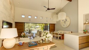 Ein modernes Interieur mit einer zentralen Kochinsel, Essbereich und Blick ins Freie.