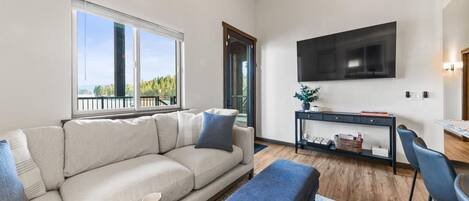A modern living room with a sofa, ottoman, and a TV mounted on the wall.