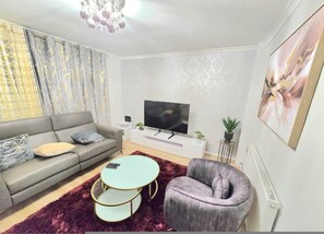 Ein modernes Wohnzimmer mit einer Couch, einem runden Couchtisch, einem Fernseher und einer Heizung.