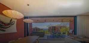Un intérieur moderne comprenant un coin repas, un grand tableau et une vue sur les bâtiments environnants.