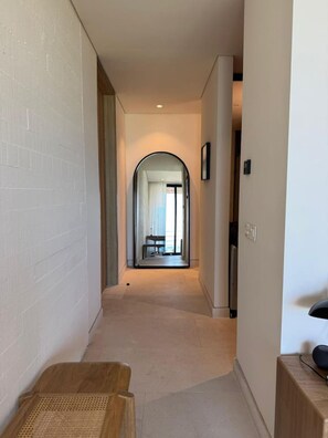 Un couloir avec un banc en bois, un miroir et une porte donnant sur une pièce.