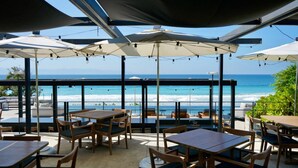 An outdoor seating area with tables and chairs, umbrellas, and a view of the ocean. - Naya 1202 Tower I in Punta de Mita (Punta de Mita)